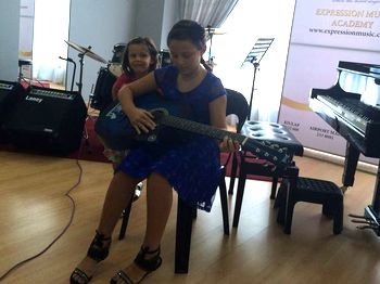 A young girl plays music on a guitar