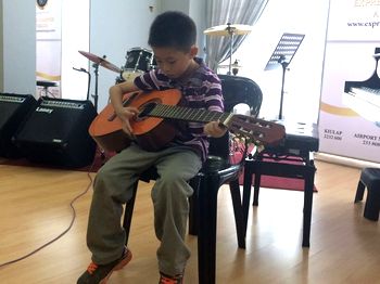 A young boy plays a guitar