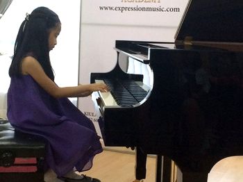 A young girl plays the piano