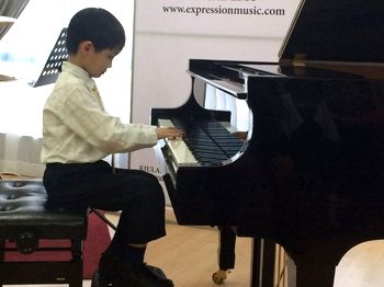 A young boy making music on the piano